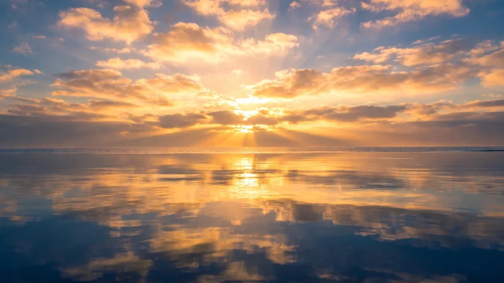Vivid sunrise over a calm ocean with warm golden light on gentle water