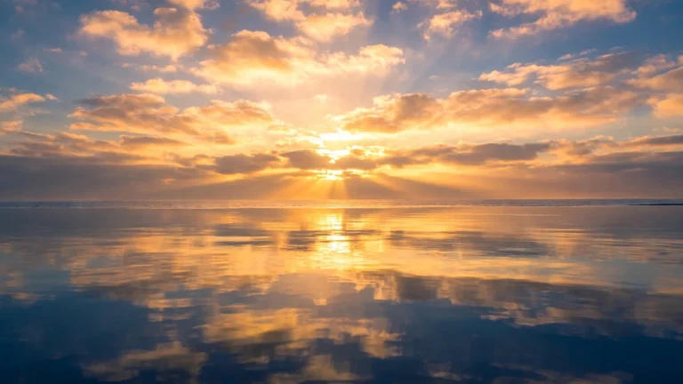 Vivid sunrise over a calm ocean with warm golden light on gentle water