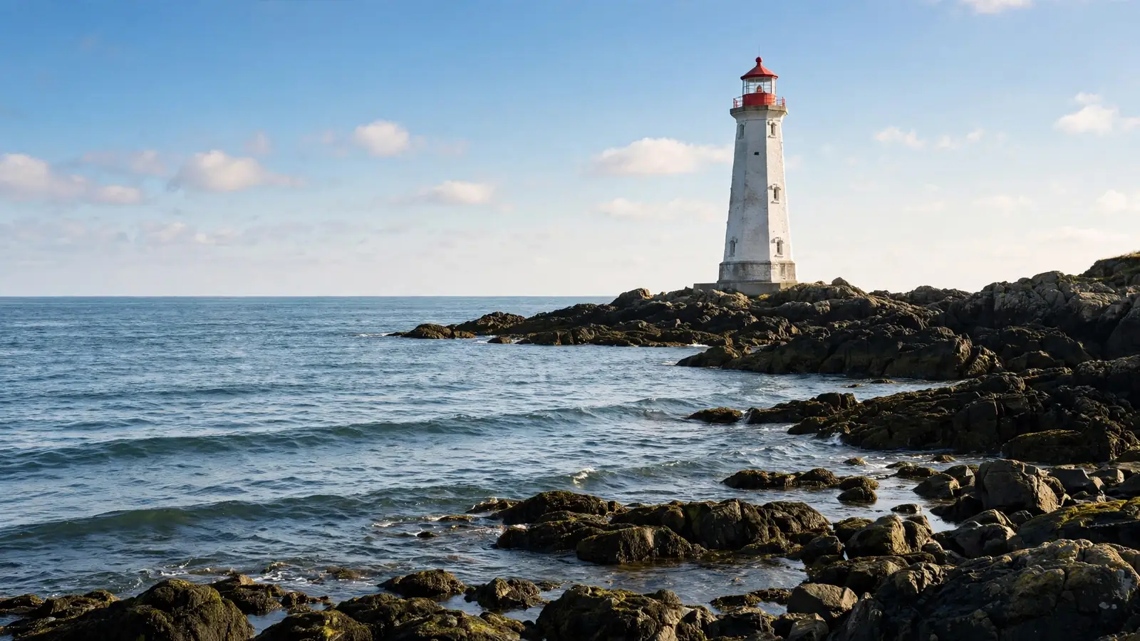 A lighthouse standing calm on a rocky coast in soft bright daylight